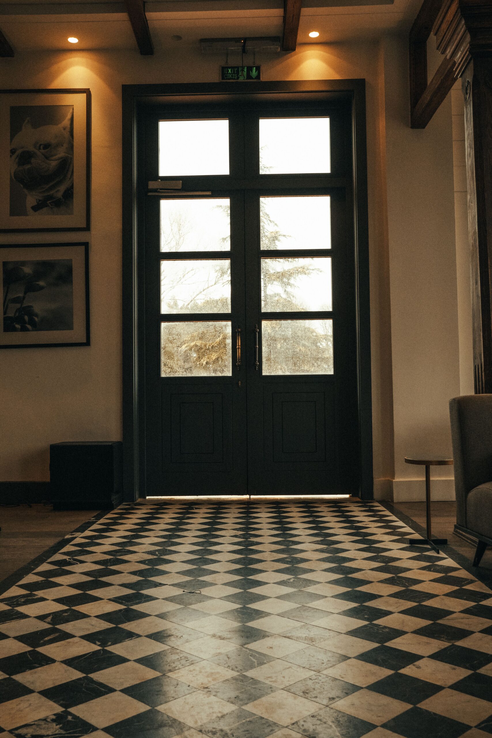 Elegant interior view of a double glass door with checkered floor tiles, enhancing classic design.