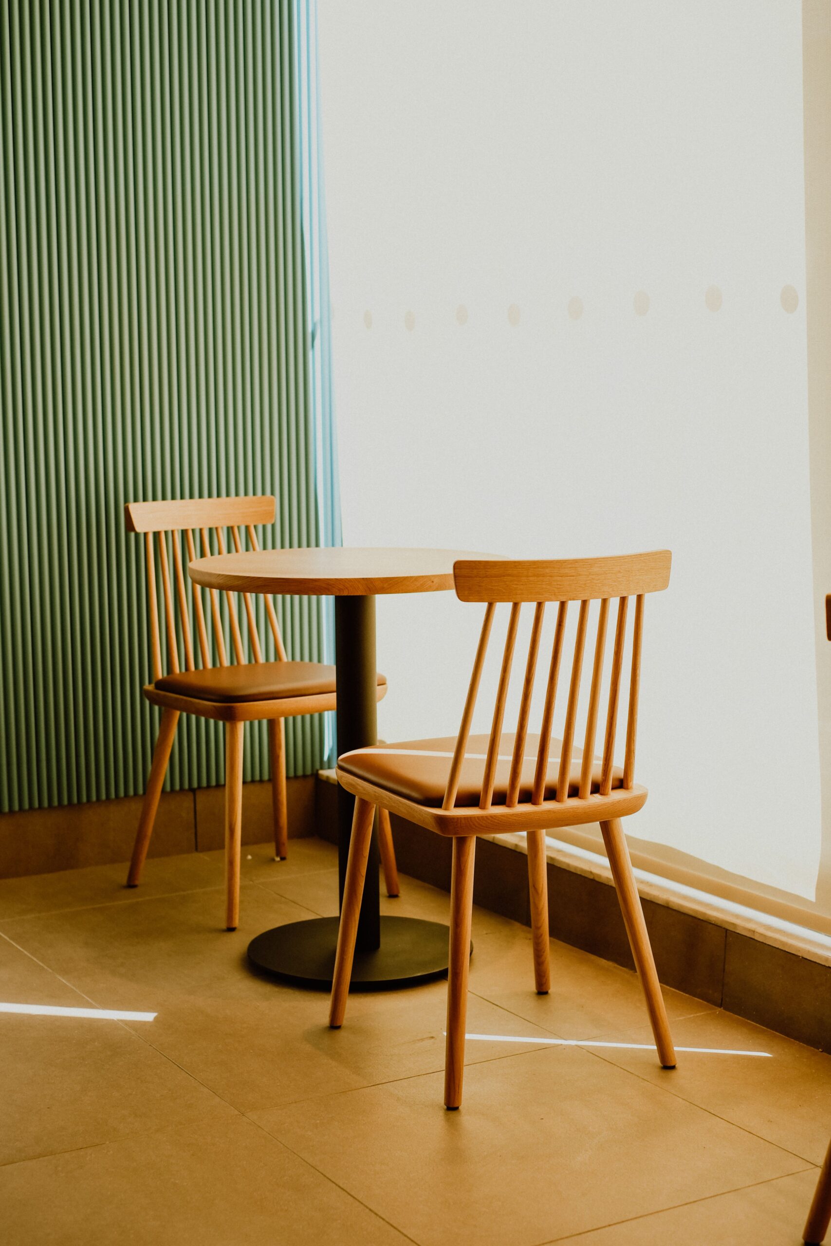 Minimalist interior design featuring wooden chairs and table in a sunlit corner.