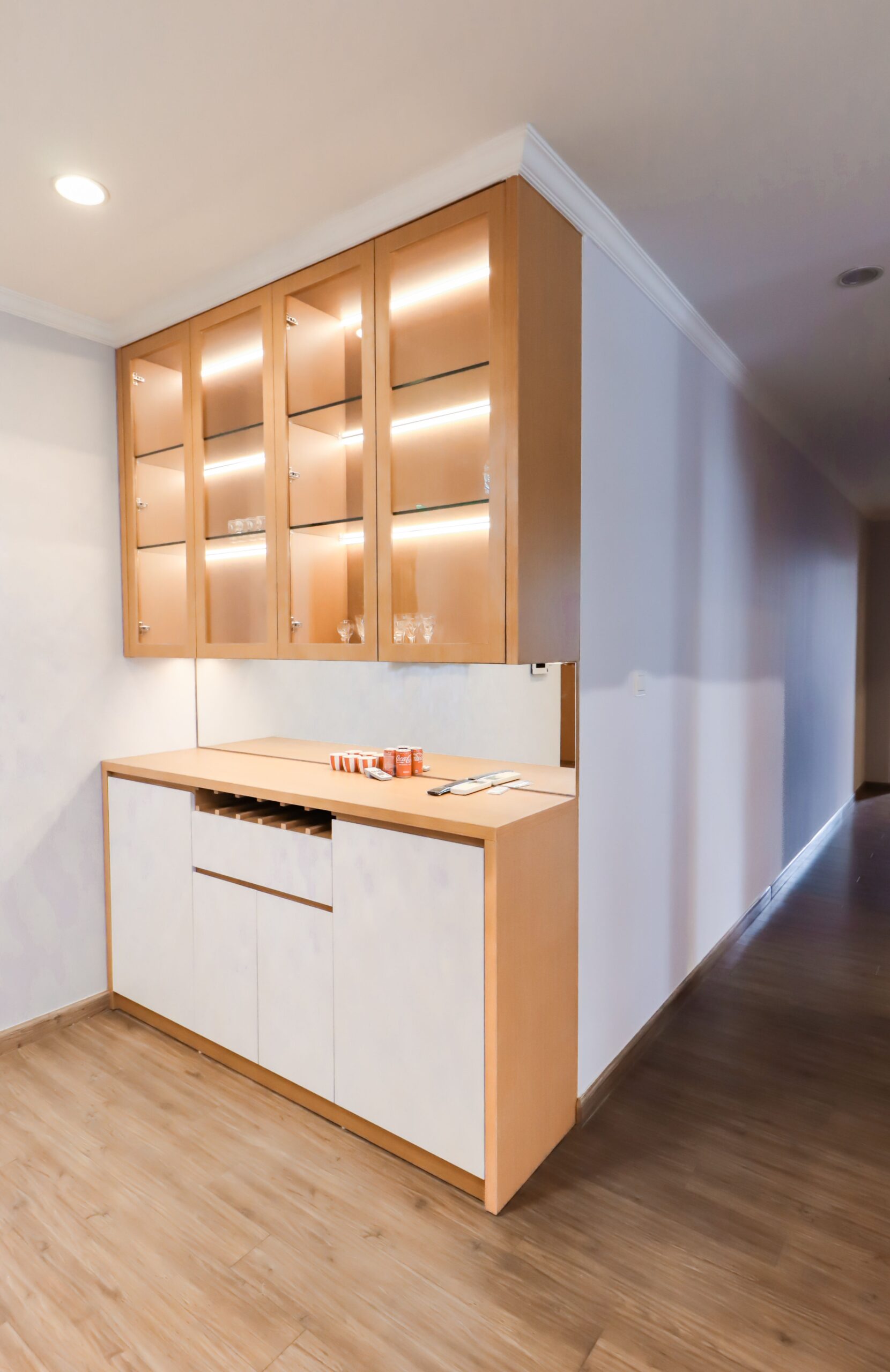 A modern wooden cabinet with glass doors in a minimalistic hallway, ideal for interior design inspiration.