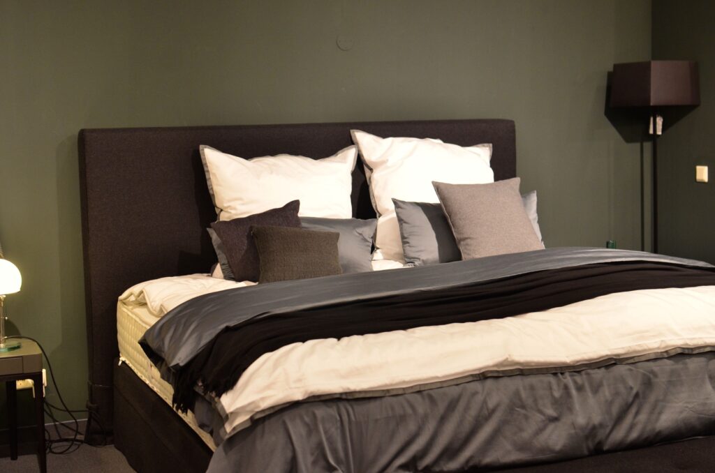 Creative design of bed with collection of cushions and cover between lamps in house