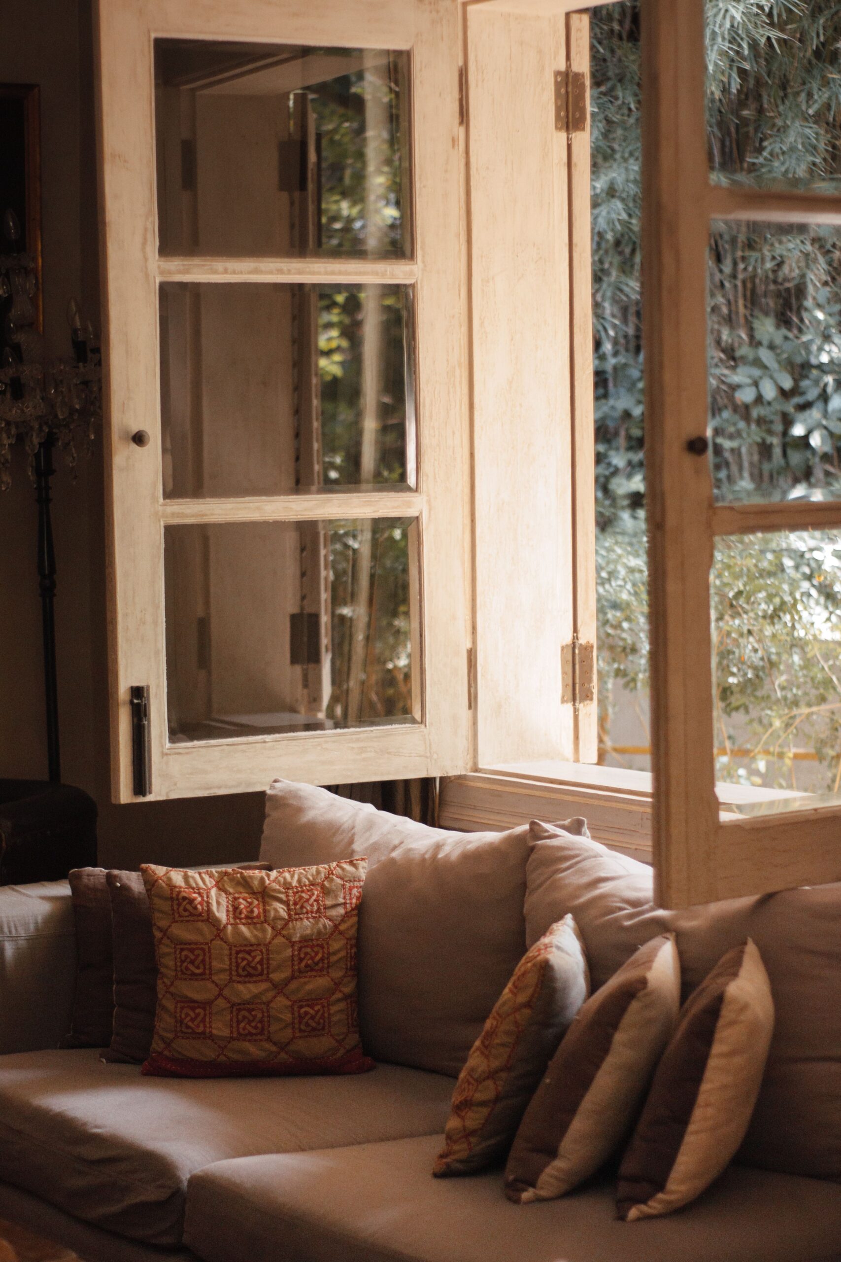 Inviting living room featuring a comfortable sofa with throw pillows and open windows, creating a warm ambiance.